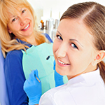 At dentist's office young nurse with adult mature woman, both looking at camera and smiling